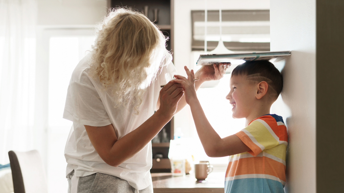 Mother Measuring the Height of Her Son