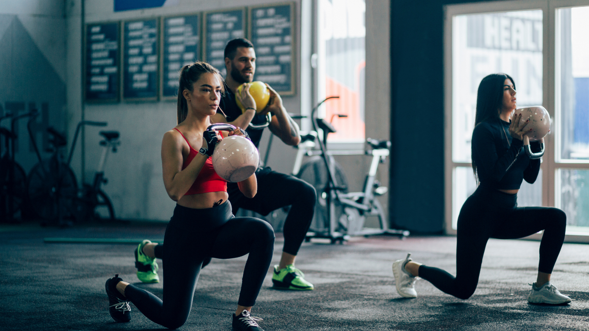 Small group of people working out in a gym - TruHeight